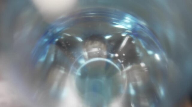 Blurry close up view looking inside a blue plastic bottle.
