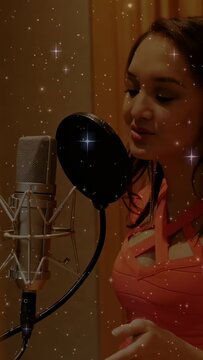 Woman vocalist entering and leaning to pop filter, singing into mic, recording with starry overlay