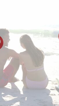 Couple sitting on sand man reaching triggers hearts floating woman leaning closer showing affection