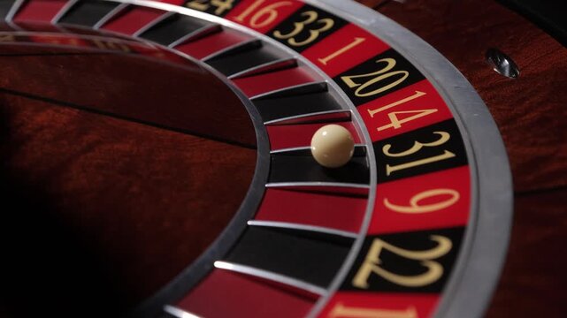 Hand spinning roulette wheel with ball in casino, close up
