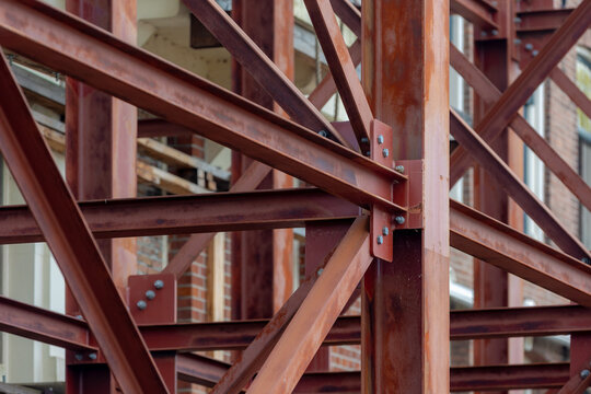 Building or houses renovate, Industrial construction site showing a complex network of rusted steel beams and girders, Bolted metal joints and structural framework against a brick building background.