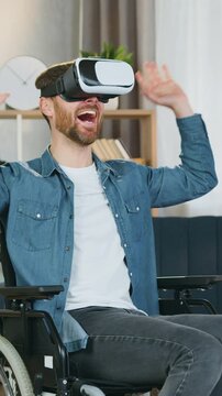 Modern technology concept where likable positive excited bearded adult Persons which disabilities guy previsioning interactive game applying augmented reality goggles in sitting room