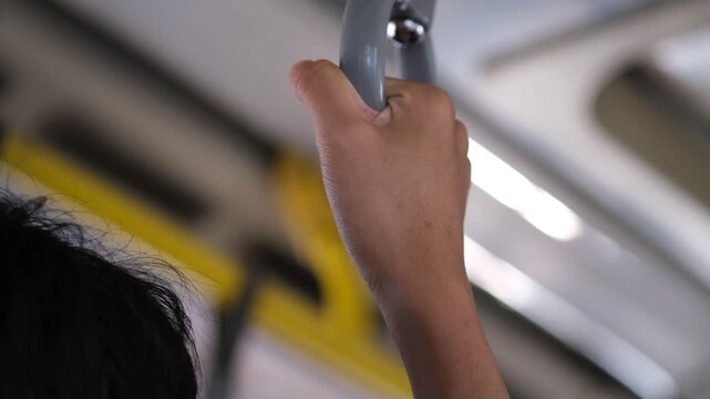 Hand grips a subway handle. Soft lighting glows behind.
