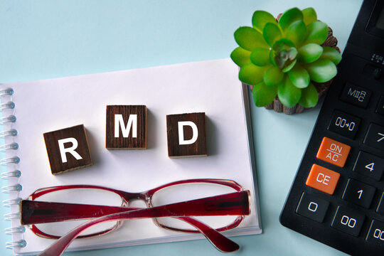 RMD - acronym on wooden cubes with a calculator and glasses in the background