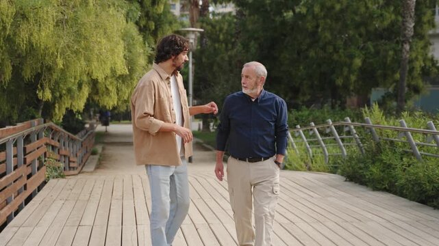 Senior father walking with his son, sharing advice and support during family conversation