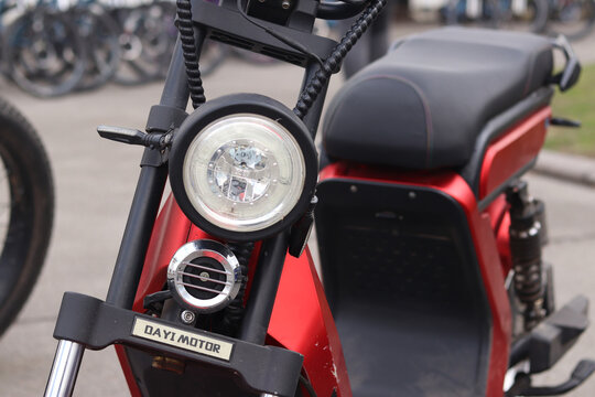 Kyiv, Ukraine - April 12, 2026: Modern Dayi Motor electric scooter in red color. Detailed plan of the front part with a round LED headlight. Red electric scooter. Urban ecological transport rental