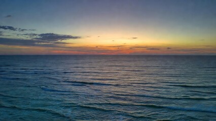 Obraz premium Sea surface reflecting pastel sunset light across horizon