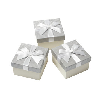 Three elegant square gift boxes with silver glitter lids and cream bases on a minimalist white studio background from above luxury celebration atmosphere