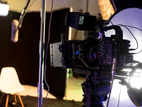 In a sleek and dynamic studio, a high-quality camera is set up for filming interviews. The atmosphere buzzes with creativity as sound equipment and lights prepare to capture engaging conversations
