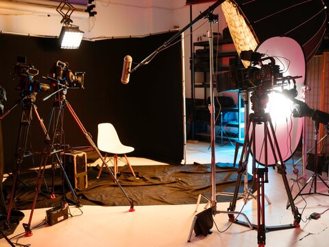 In a vibrant studio designed for interviews and podcasts, cameras and microphones are perfectly arranged. The black backdrop and bright lights create an inviting atmosphere for engaging conversations