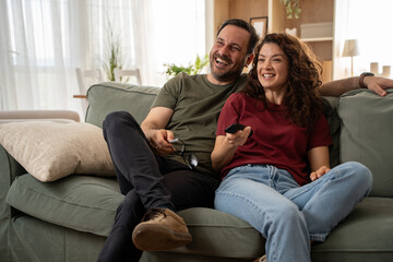 Obraz premium Smiling couple enjoying tv shows and films on streaming service in living room