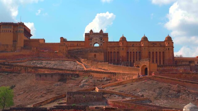 A wide static shot of the majestic Amber Fort (Amer Fort) in Jaipur, showcasing its massive structure on the hillside with the unique zigzag pattern of its long defensive walls.