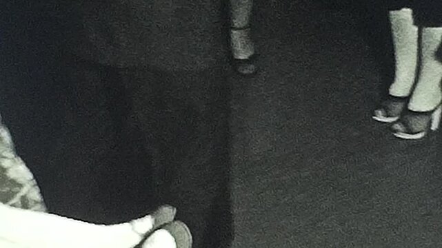 Vintage-style 8mm film footage showing dancing feet in stylish shoes. The grainy, black-and-white aesthetic captures the nostalgic charm of mid-20th century social gatherings.