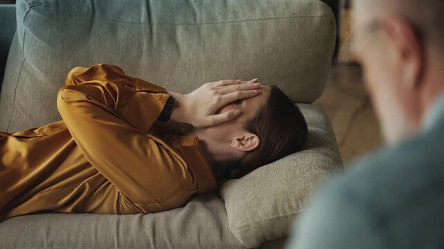 Upset young woman crying while sharing her life problems with psychotherapist