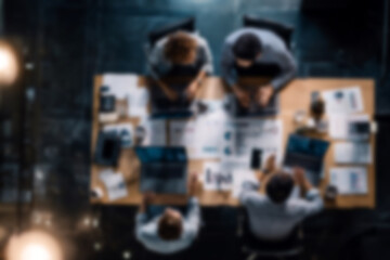 Fototapeta premium Blurred Diverse team collaborating on project with laptops and documents in modern office