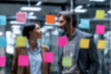 Fototapeta premium Blurred Business colleagues collaborating with colorful sticky notes in modern office