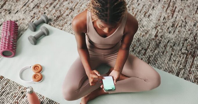 Pilates, woman and scroll with phone in home for exercise break, check notifications and wellness app. Fitness, mobile screen and black girl browsing on mat for workout video, text message and above