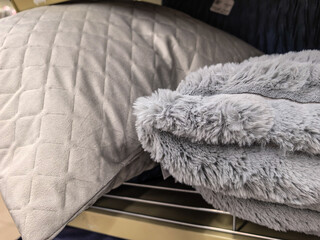 Fototapeta premium Soft gray pillow and fluffy blanket on store shelf