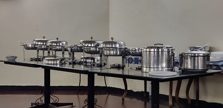 Row of stainless steel chafing dishes and food warmers set up for a professional catering event