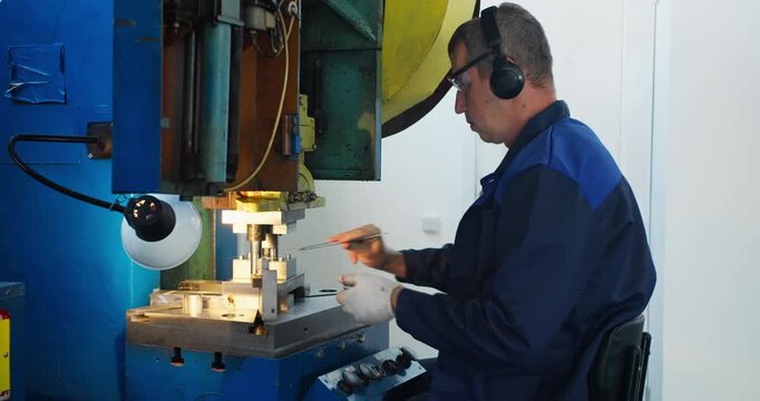 Industrial operator working at stamping machine in factory. Blue collar job and metalworking production