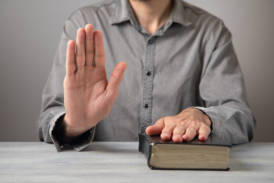 Man taking oath with hand on book.