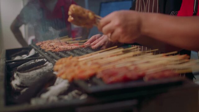 The chef grills satay meat on skewers. Street food in Asia, delicious dishes at local markets, travel and tourism.
