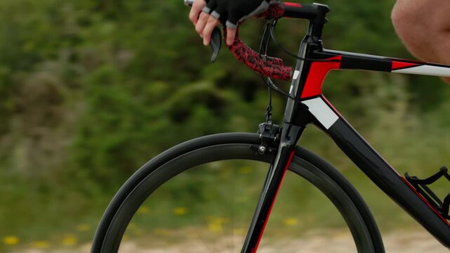 Male hands holding bicycle handlebars while riding close-up. Cycling sports, outdoors, healthy lifestyle.
