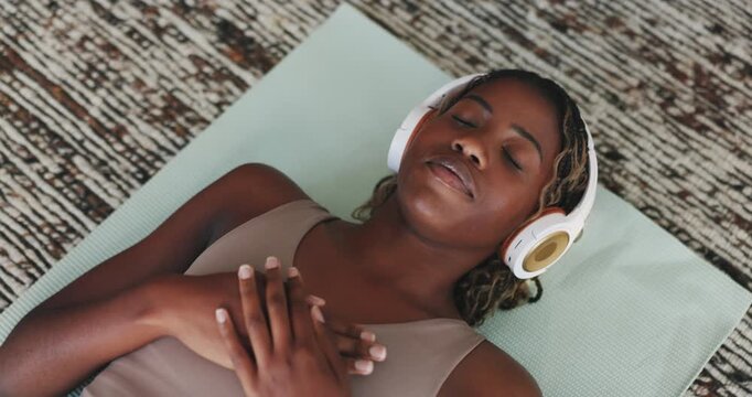 Above, breathe and black woman with headphones on floor for calm, peace and mindset in home. Podcast, wellness and person with breathing exercise for healing, mindfulness and guided meditation