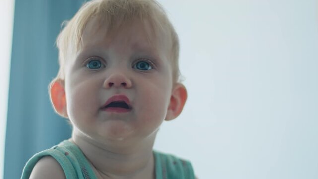 Portrait of infant girl in close-up with focused look. Baby growth and early childhood development at home