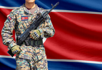 Naklejka premium North Korea flag with soldier holding assault rifle