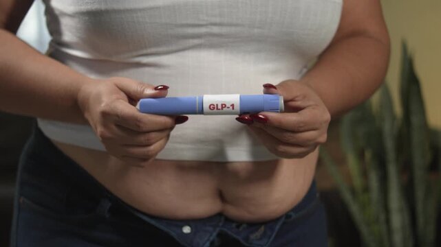 Close-up of overweight woman holding GLP-1 pen injector for self-injection, obesity care and diabetes prevention