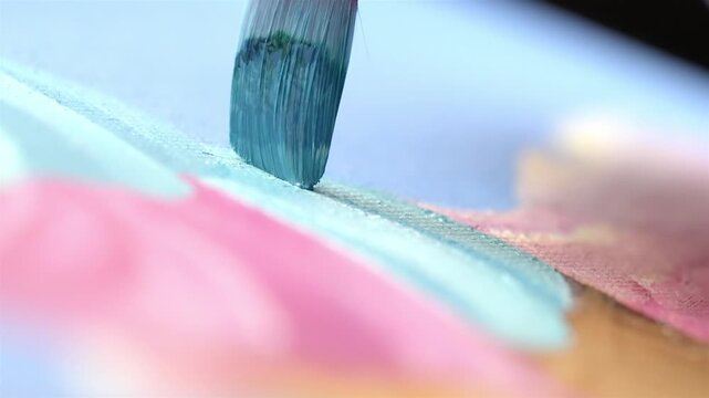 Extreme macro shot showing a paintbrush with blue paint on the artwork
