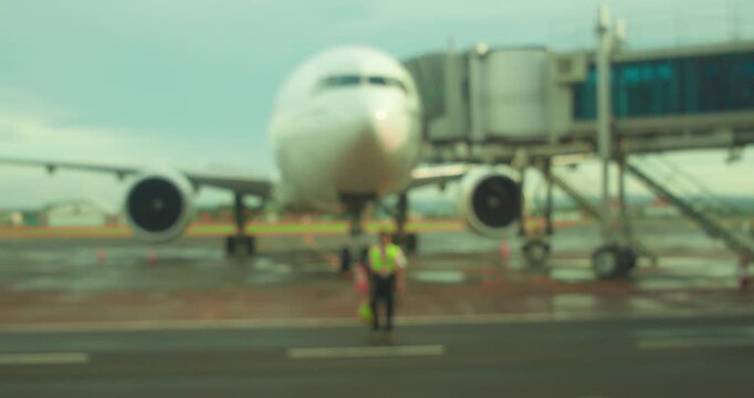 Defocused blurred view of ground crew worker walking near passenger jet on runway in Airport
