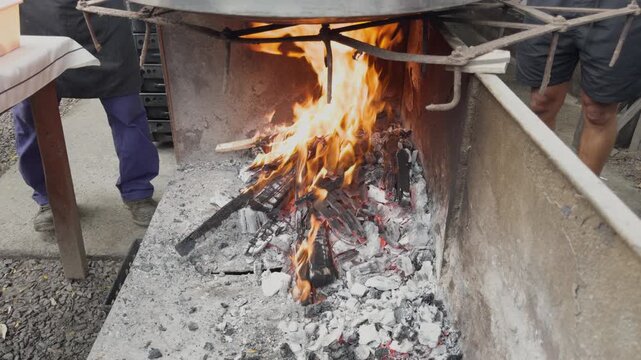 Outdoor cooking with firewood burning in a large barbecue pit