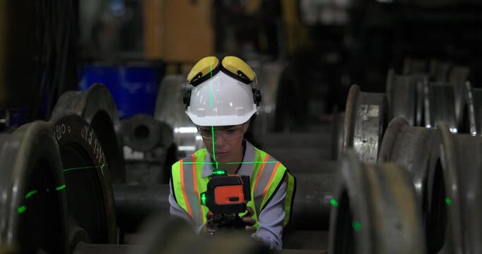 A locomotive engineer in a factory setting uses a laser measuring tool, demonstrating the precision and technical skills required in industrial engineering and construction environments.
