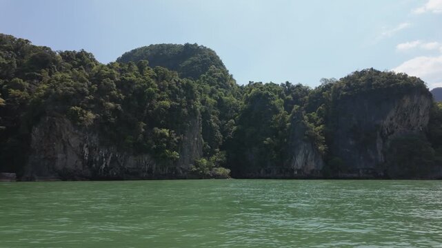coastal landscape featuring lush greenery and rocky cliffs reflected in calm sea on longtail boat running , travel articles, nature blogs, or relaxation themed content