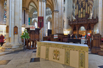 A wide interior shot of a grand cathedral, featuring tall stone columns, a wooden pulpit, and an ornate altar table in the foreground in Beverley Minster - Yorkshire - Great Britain © Robert