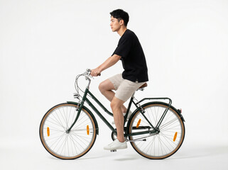 Obraz premium Young man in casual clothes riding a vintage dark green city bicycle, wearing black t-shirt and beige shorts, looking forward, side view full length, isolated on white background