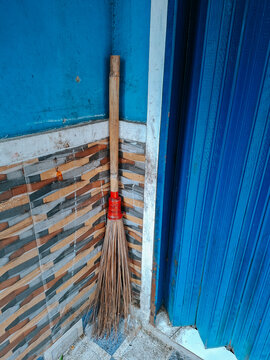 a broom made from the midribs of coconut leaves, leaning against a corner.