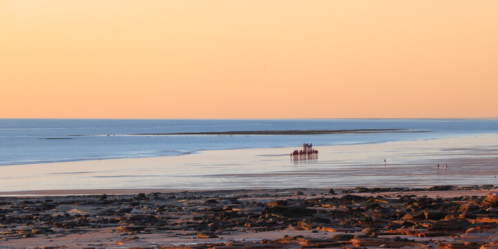 Broome, Western Australia, Australia - April 4 2026: Famous Cable Beach at sunset. Travel, tourism, vacation, holiday hot spot. Tourist riding camels in distance. Copy space