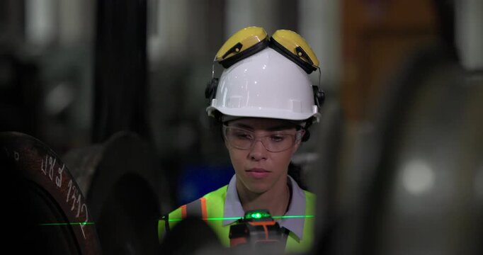 A locomotive engineer in a factory setting uses a laser measuring tool, demonstrating the precision and technical skills required in industrial engineering and construction environments.
