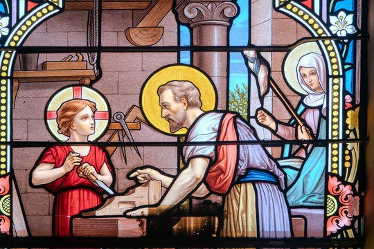 Stained glass of Holy family: Jesus infant, Virgin Mary and St Joseph in the workshop of Joseph the carpenter.