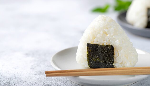 白い皿に置かれた塩むすびのおにぎりと箸のミニマル和食イメージ