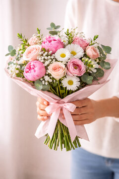 Close-up of hands holding fresh flower bouquet, Mother&rsquo;s Day gift concept, soft natural light, clean neutral background.