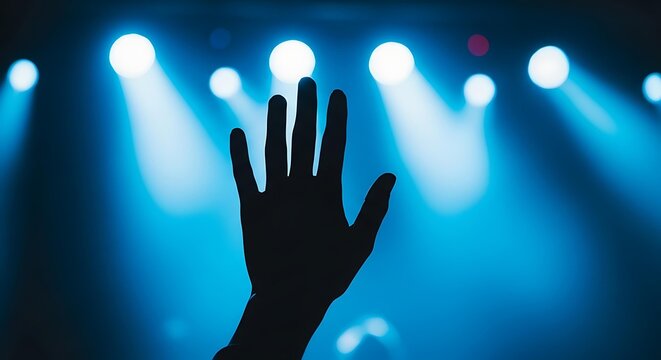Silhouette of a single hand raised in a crowd with bright blue stage flares, cinematic hand silhouette at a music performance with glowing spotlights, minimalist hand silhouette for worship 