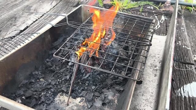A dramatic view of vibrant orange and yellow flames rising from an open fire. The video captures the intense heat and glowing embers of a controlled burn.