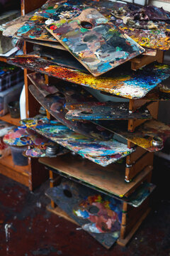 An old palette with oil paints in the artist's studio. Painted background created by a creative person. 