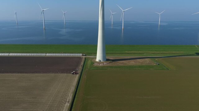 Aerial view of wind turbines and tractors in dutch polder