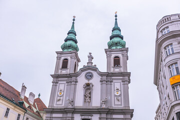Fototapeta premium Baroque church facade with twin copper domes and ornate statues of cultural heritage, Vienna