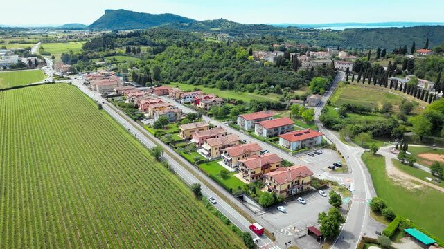 Aerial view of small town in Costermano sul Garda surrounded by vineyard fields, roads and green hills, Italy